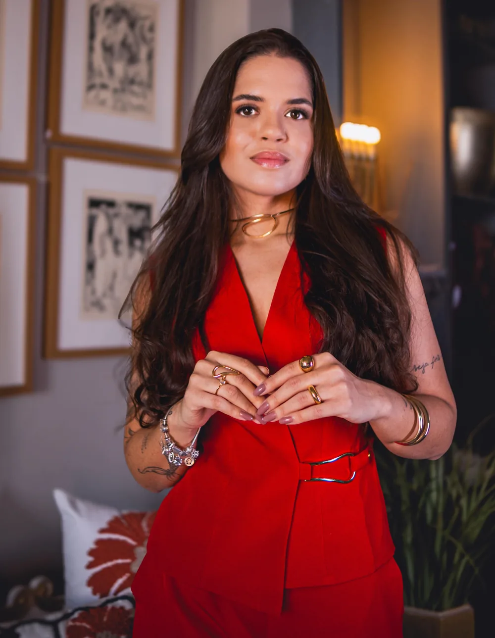 Dra. Raquel Dórea, advogada, de colete vermelho e cabelo longo, com as mãos unidas à frente do corpo.